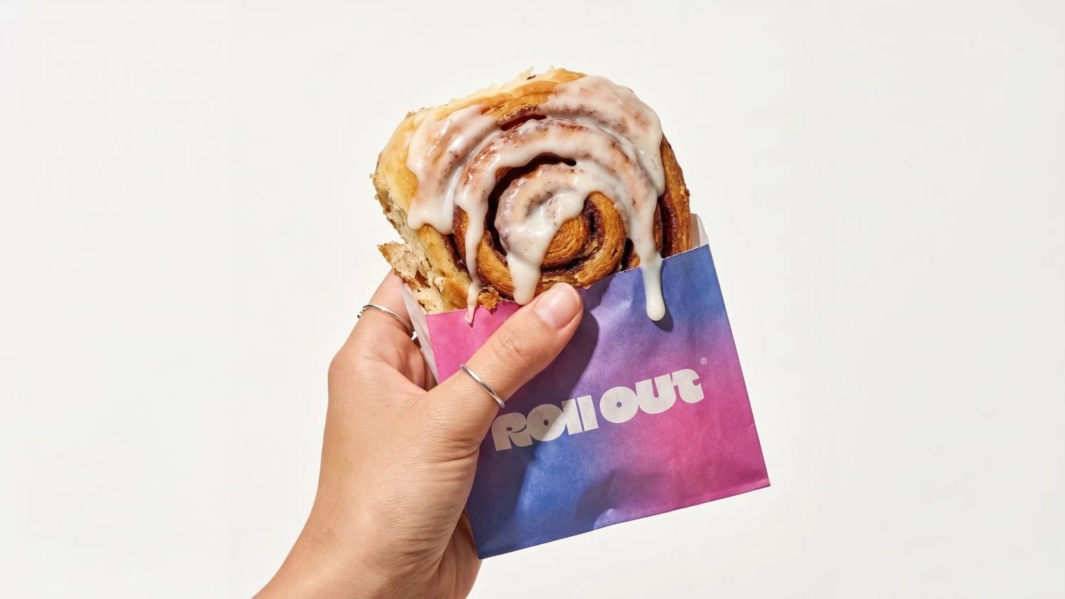 A Rollout cinnamon roll in a branded sleeve